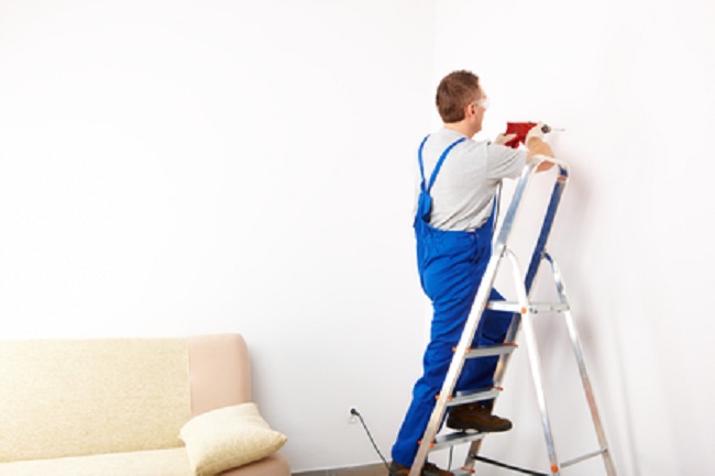 Man with drill working on ladder